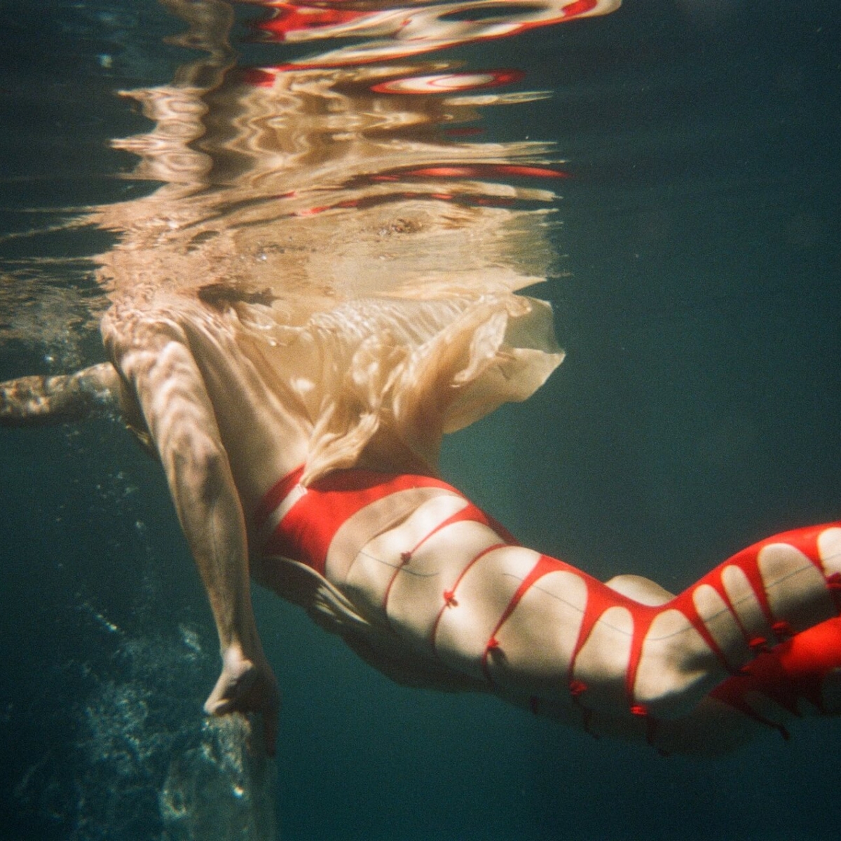 person swimming wearing red ripped tights 