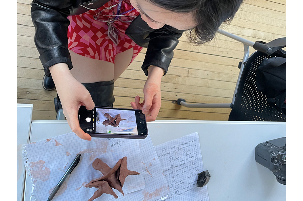 A person taking an overhead photo of a clay object