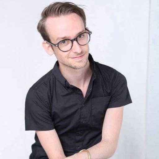 Tyler Bugg headshot white man with blonde/brown hair, glasses and black shirt