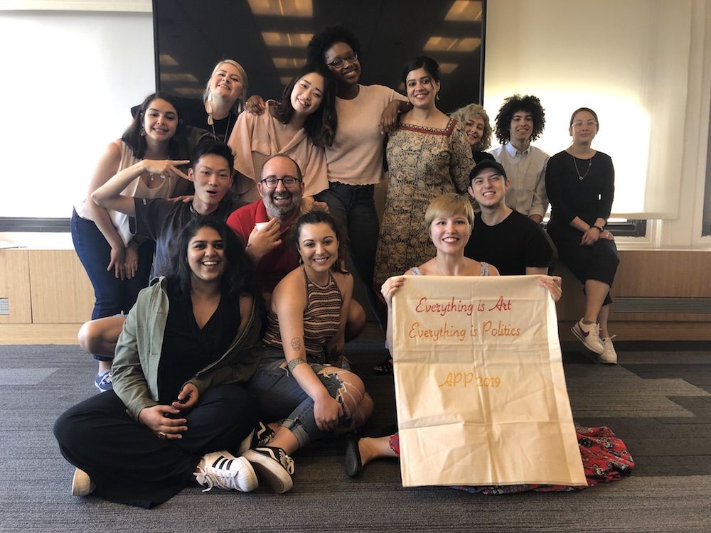 Large group photo holding banner reading "Everything is Art, Everything is Politics"