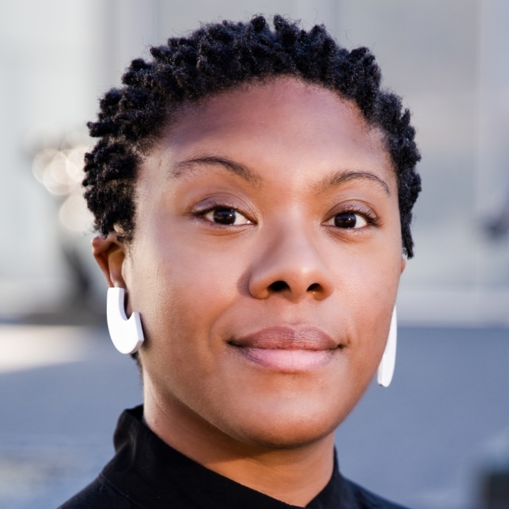 Lauren Nixon smiles at the camera, she has short dark hair and wears hoop earrings. 