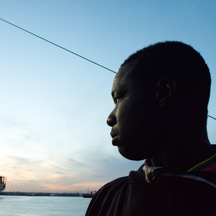 A man looking away at a boat in the distance.