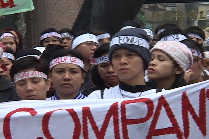 A group of women in a demonstration holding up a sign that is cutoff