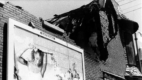 A billboard on the side of a deteriorating building.