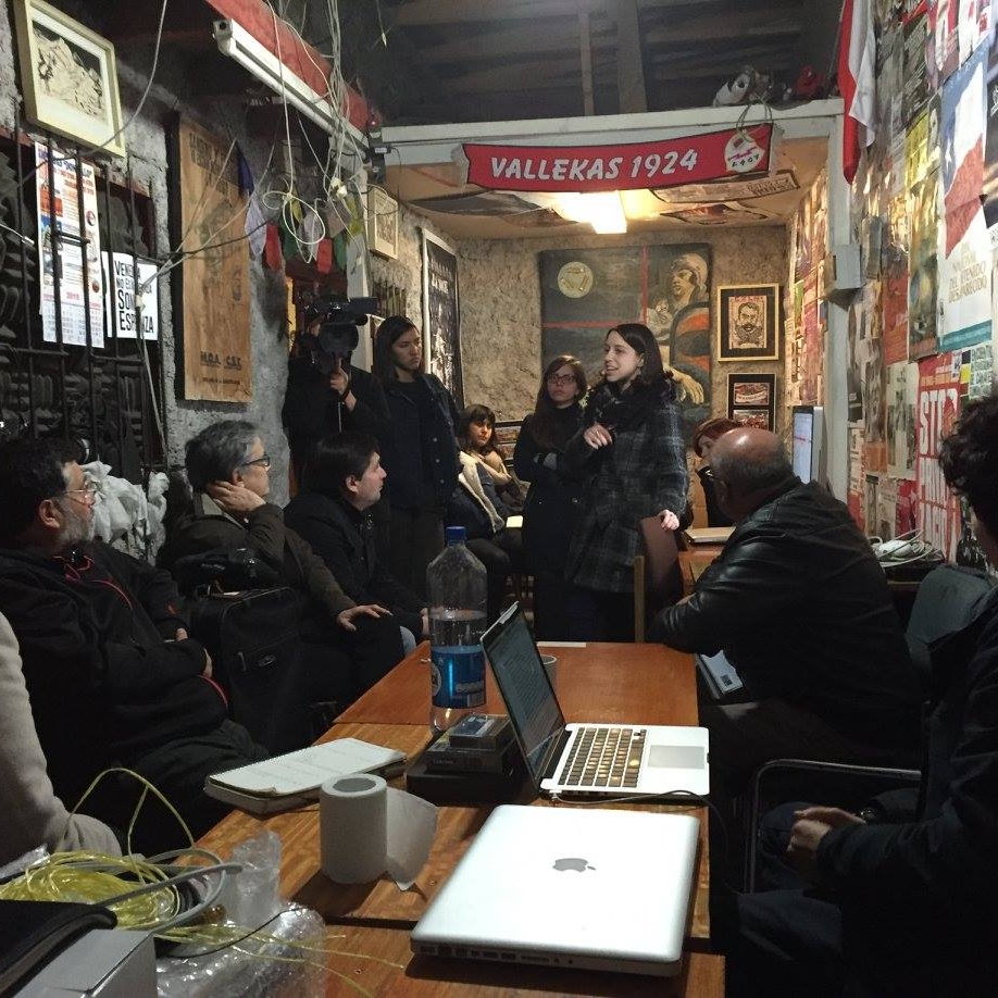 People sitting around a table listenng to two speakers.