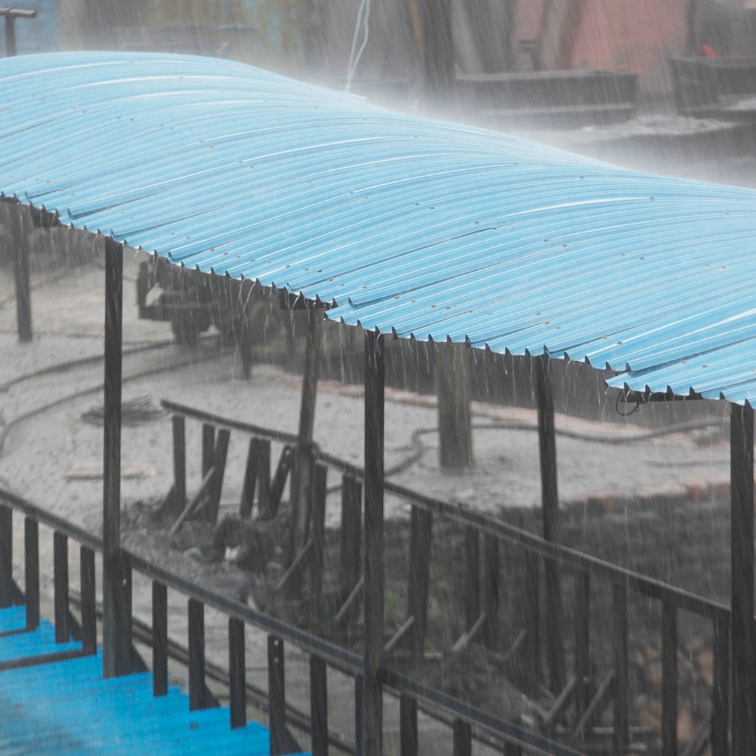 A blue covered wooden bridge in the rain