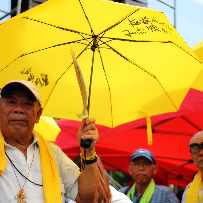 Three men holding bright yellow and red umbrellas