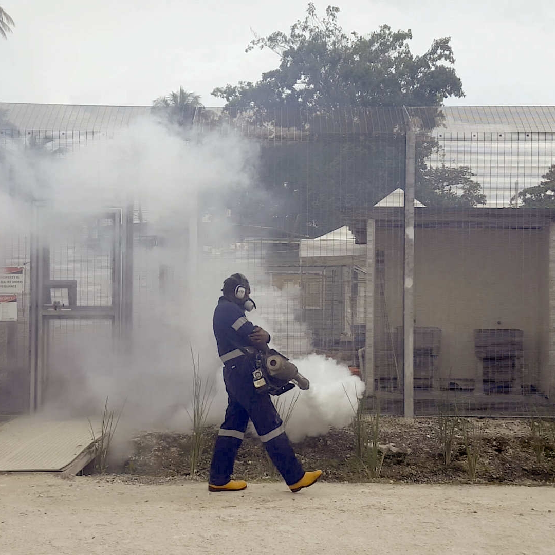 Person in a hazmat suit wearing a gas mask walking in front of a detention facility.