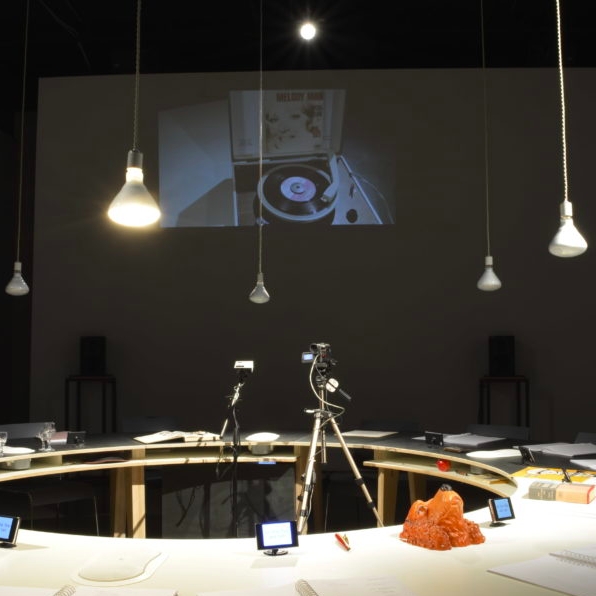 Round table in the center of the room with cameras and papers on top