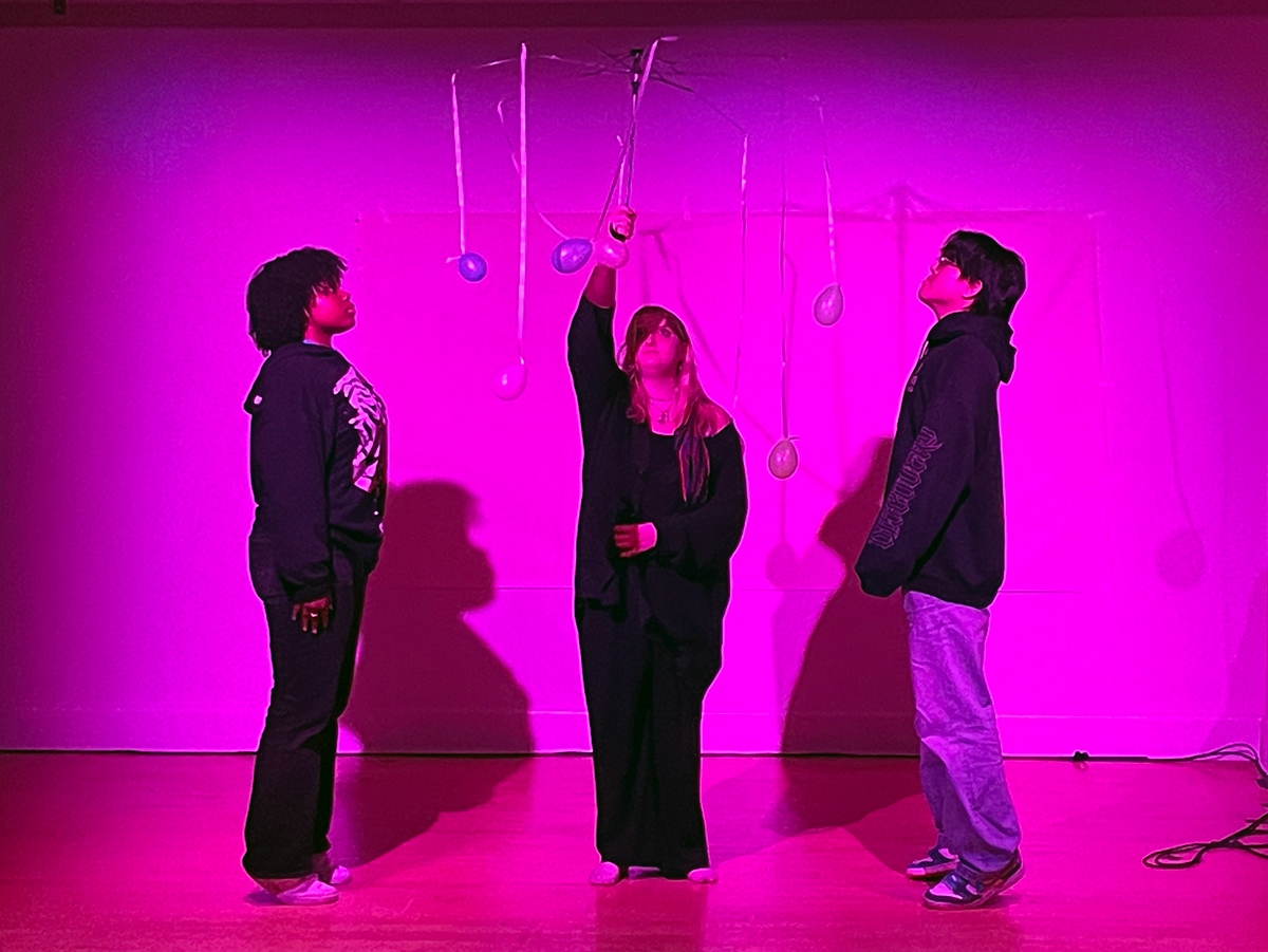 Students stand under a bright pink light