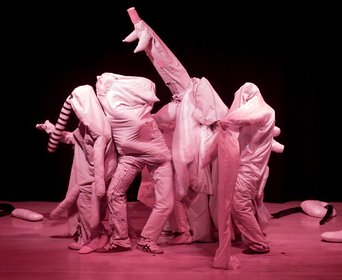 Students covered in various fabrics intertwine to form a creature