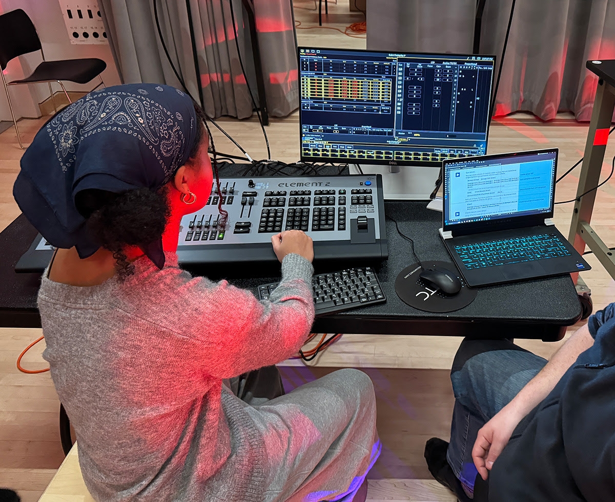 A student learns how to use a lighting board for theatrical lighting