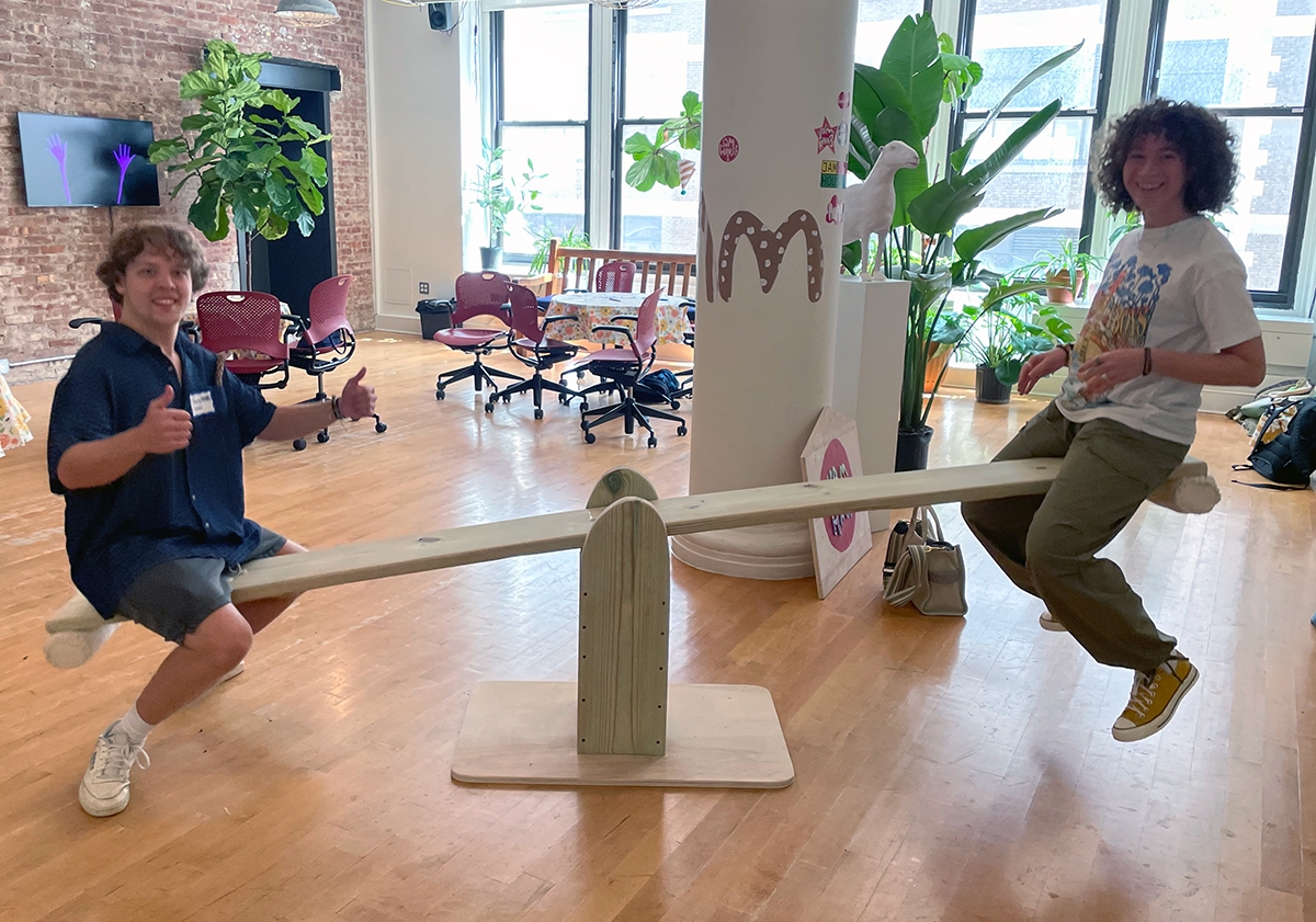 Two students sit on a seesaw in the 4th floor lobby