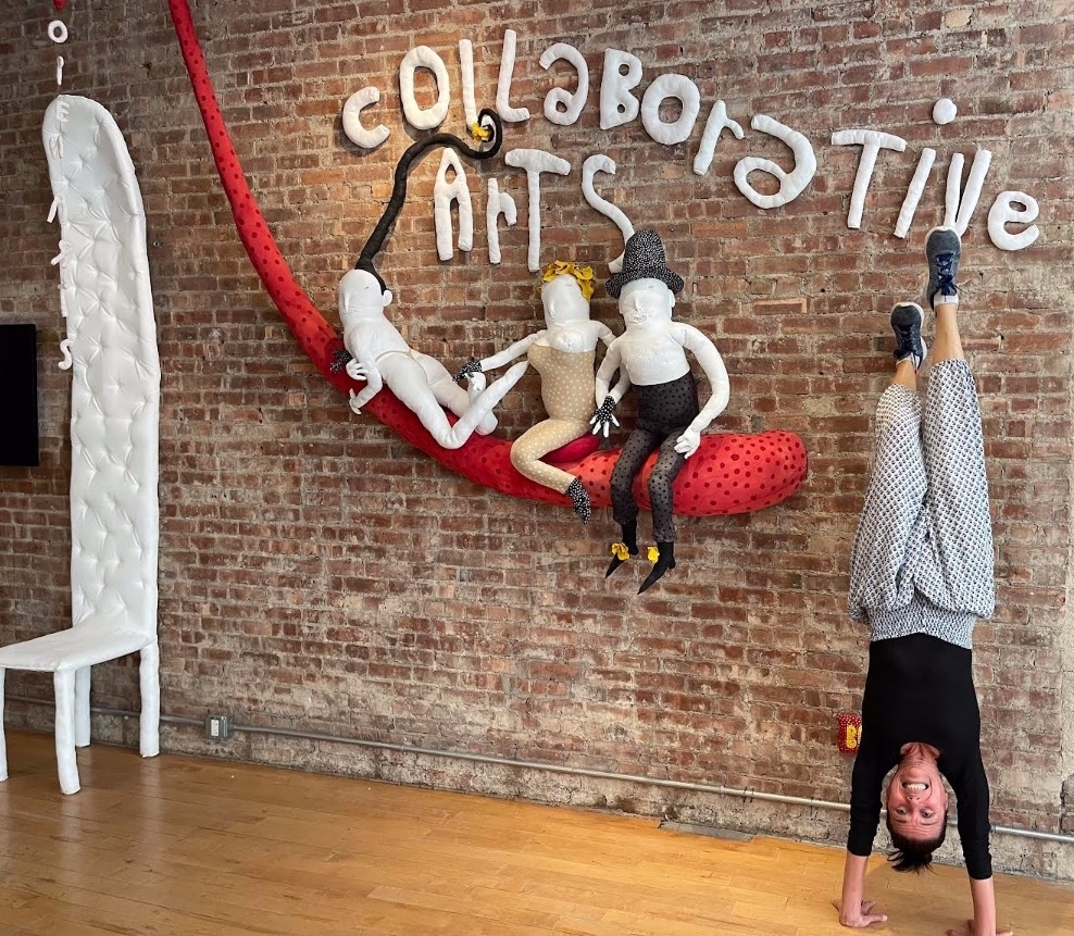 Prof. Pat Hoffbauer does a handstand next to the floor welcome sign