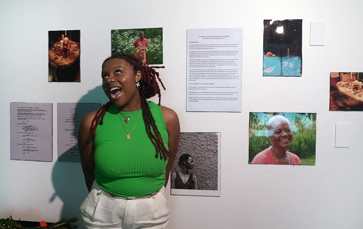 Damayanti stands in front of a wall with photos and text