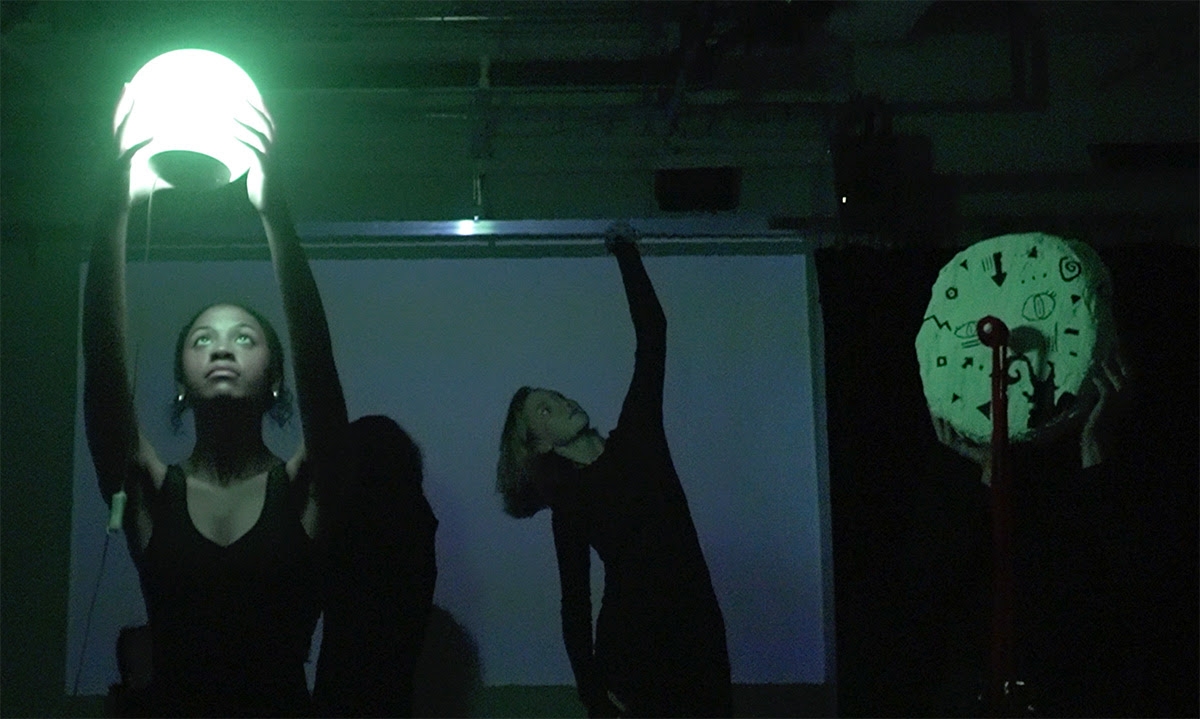 Student holding a glowing orb with dancers in the background