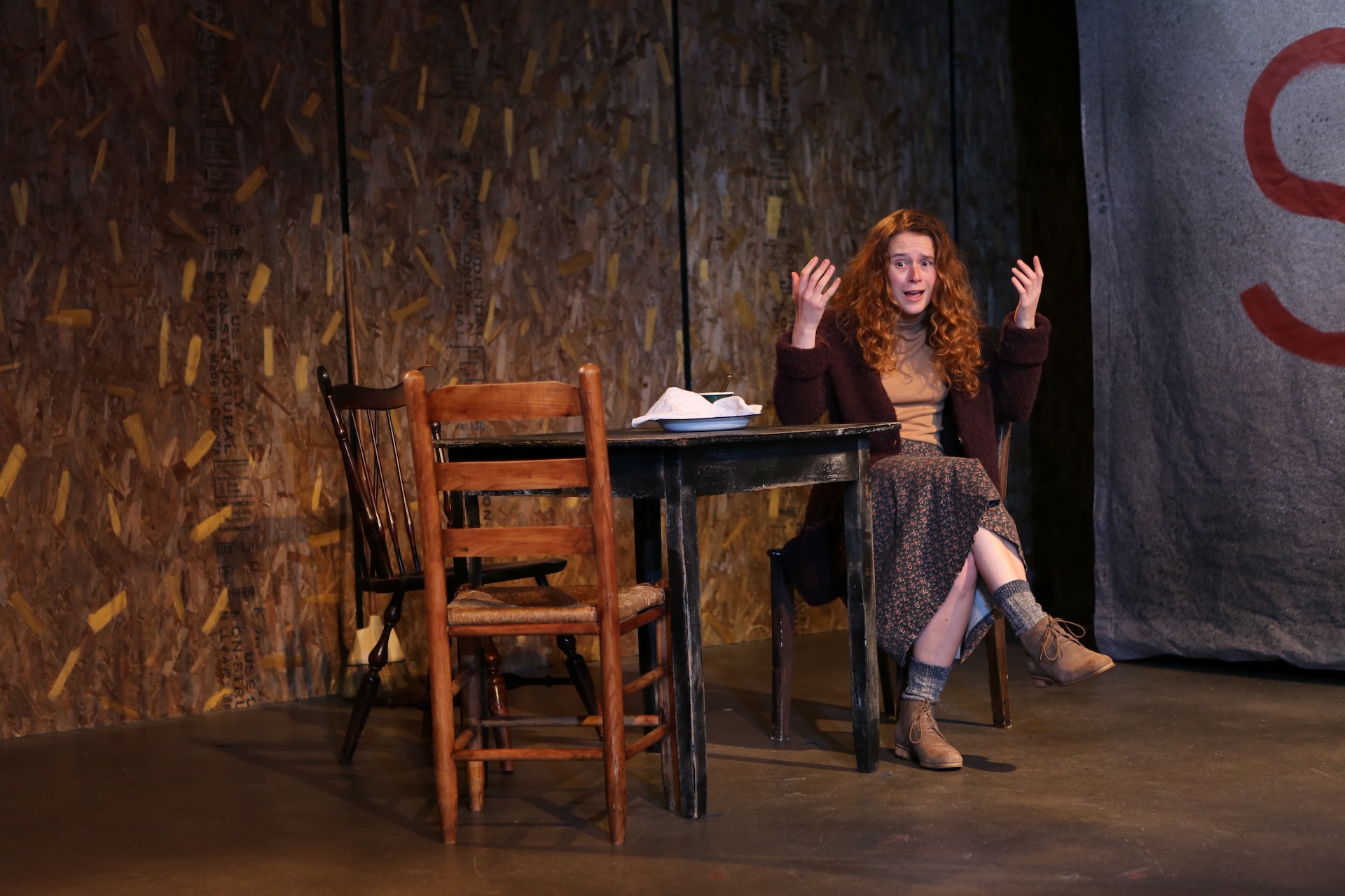 Actress seated on stage.