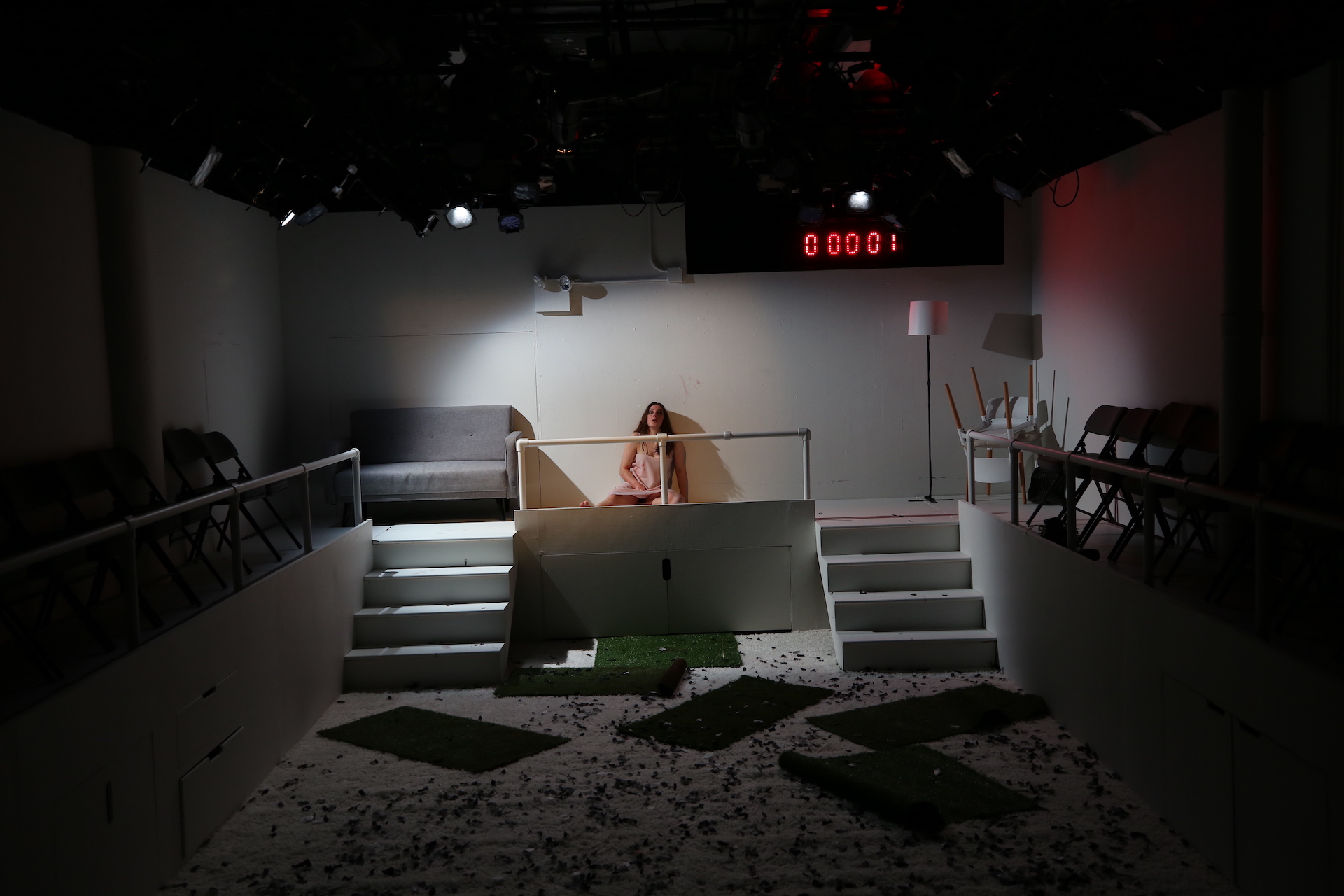 Woman sits against a white wall at the top of white steps