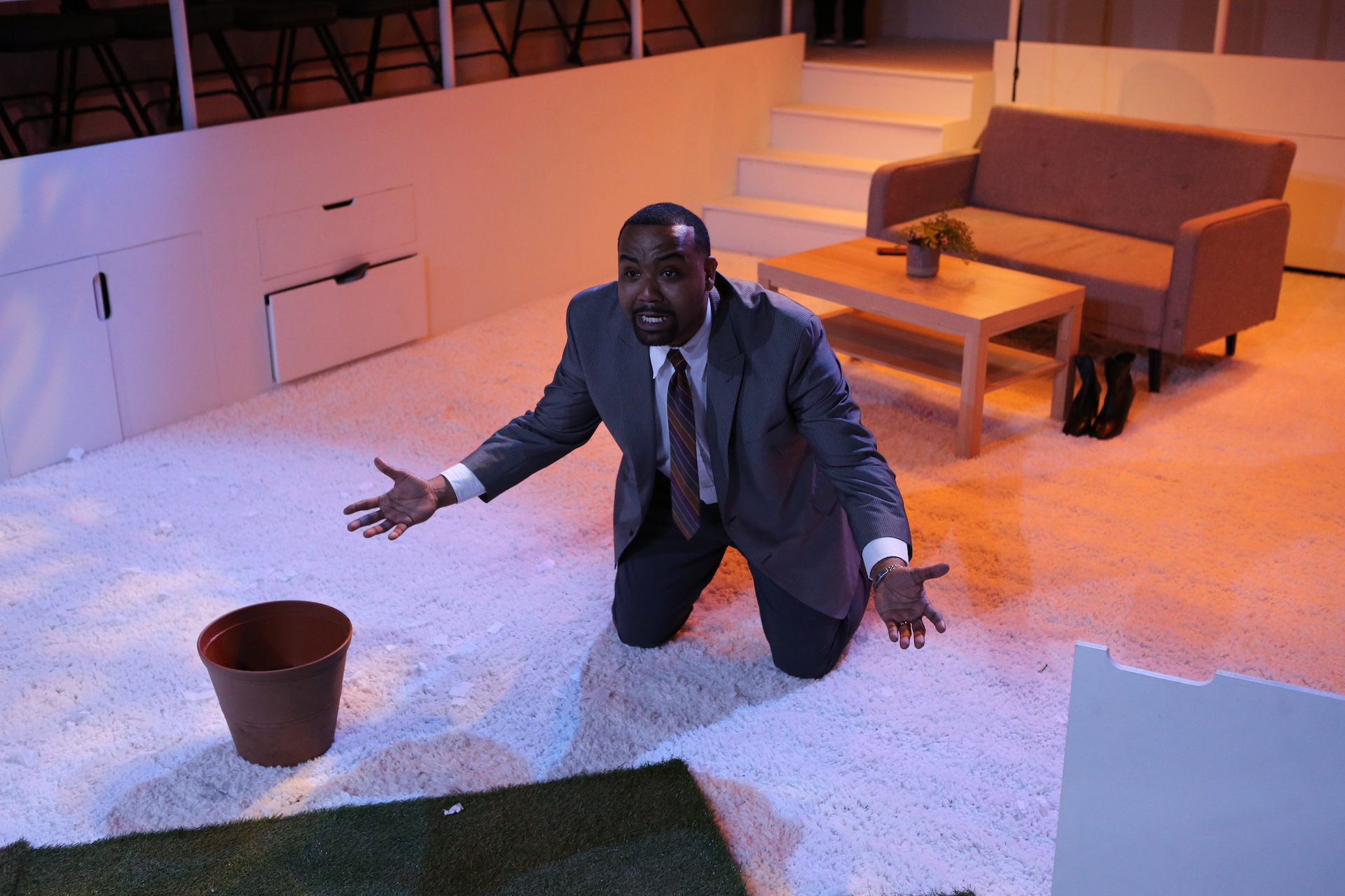 Man kneels on carpet with his arms outstretched 