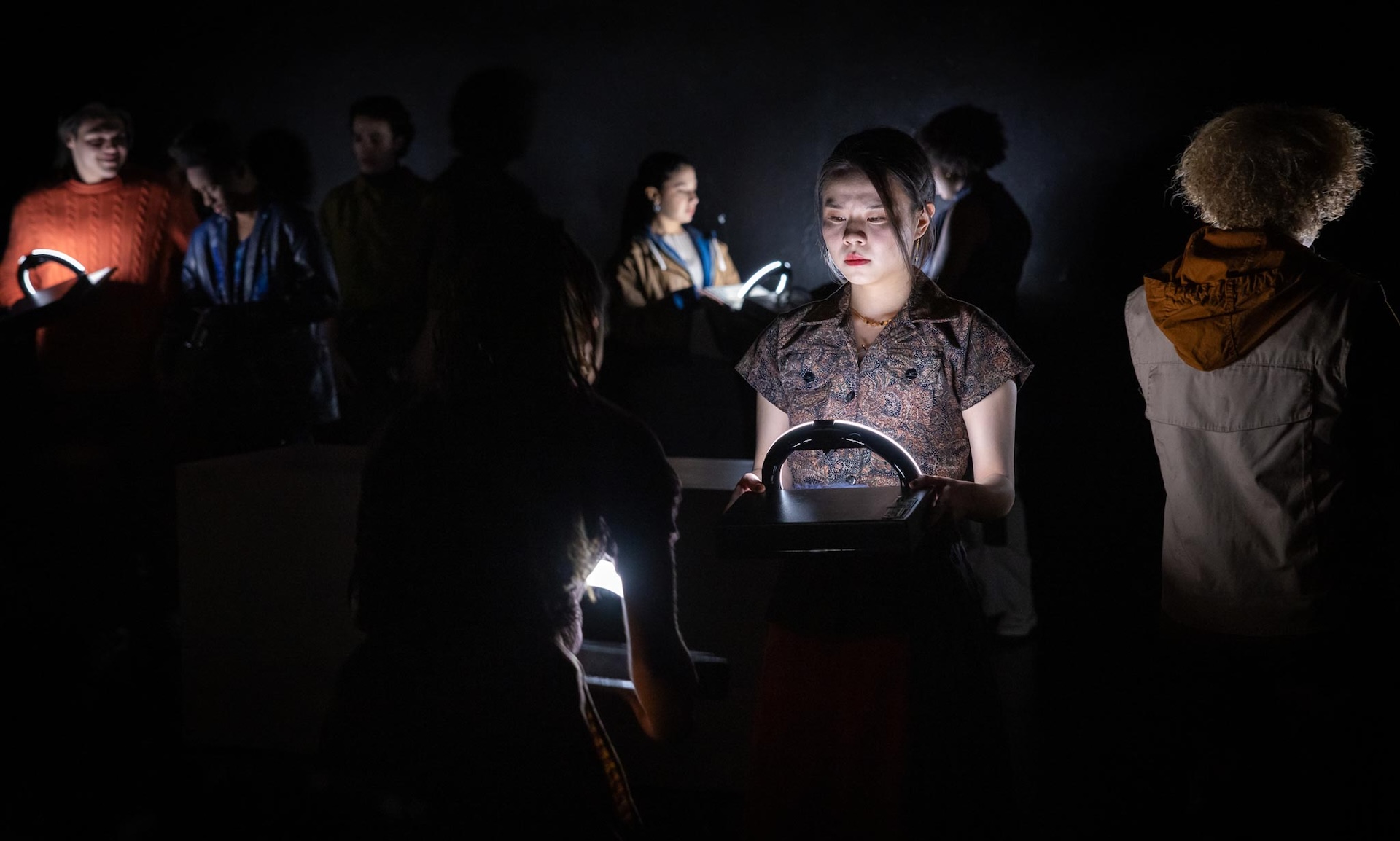 actors standing in the light emanating from laptop props 