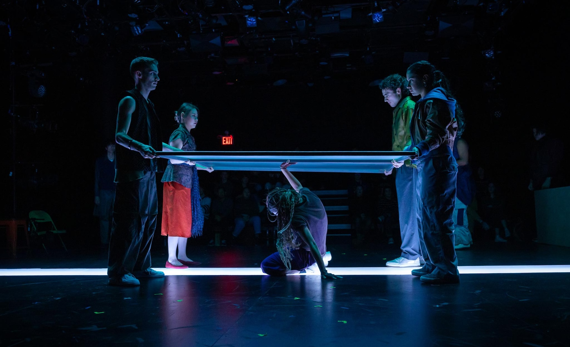 actor crouching under screen with four other actors holding corners of screen