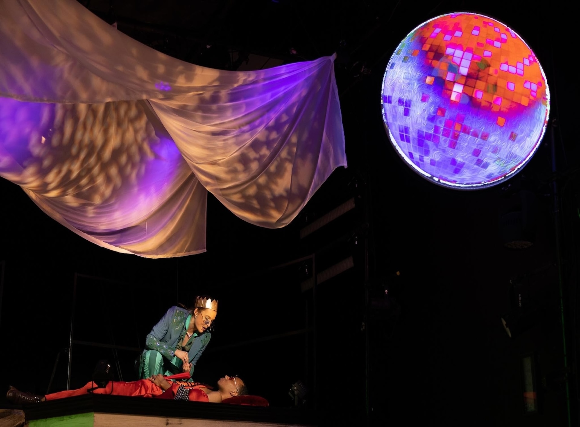 actors lying under bright moon with fabric hanging above their heads