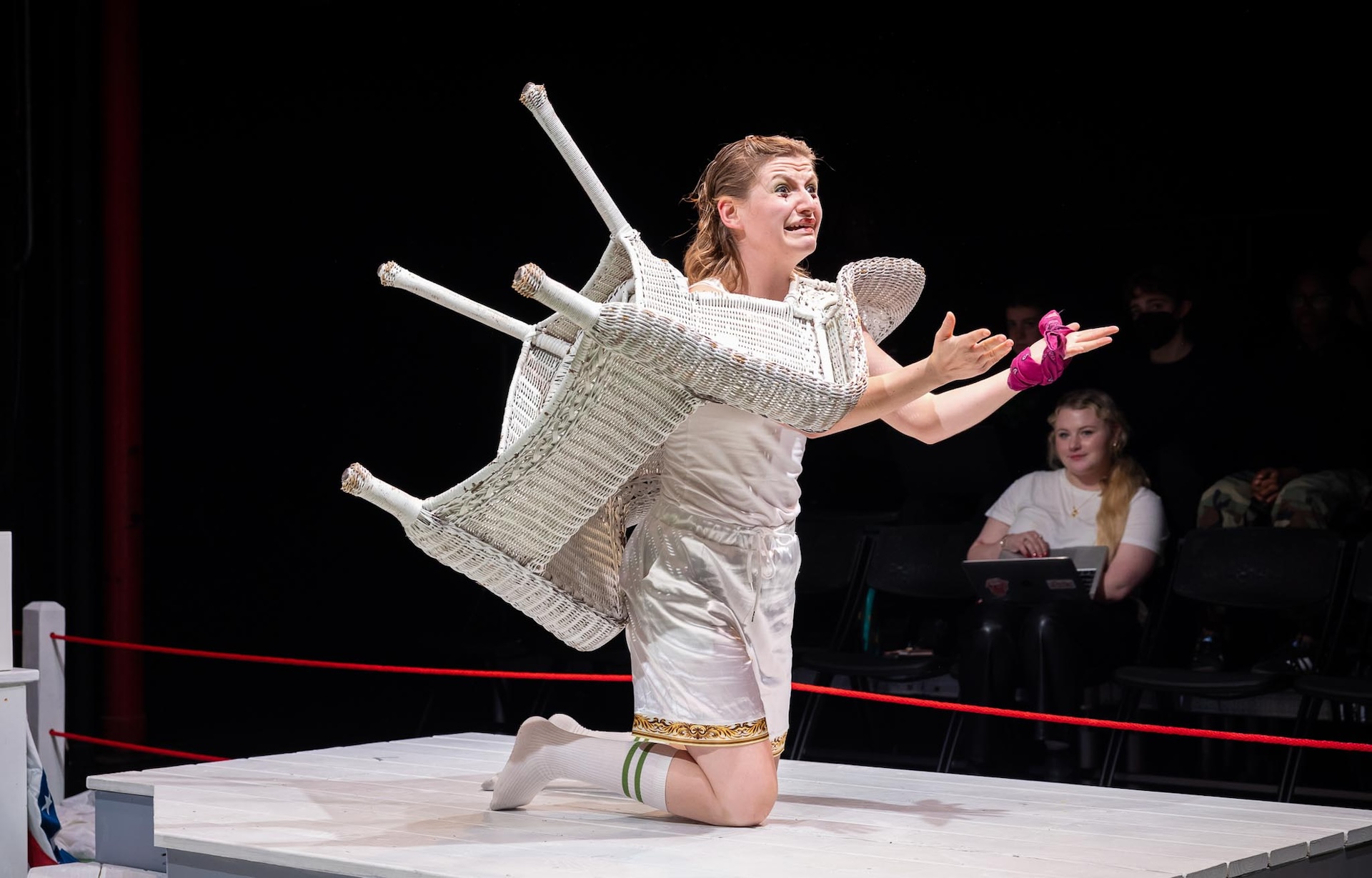 actor kneeling down stuck through a wicker chair