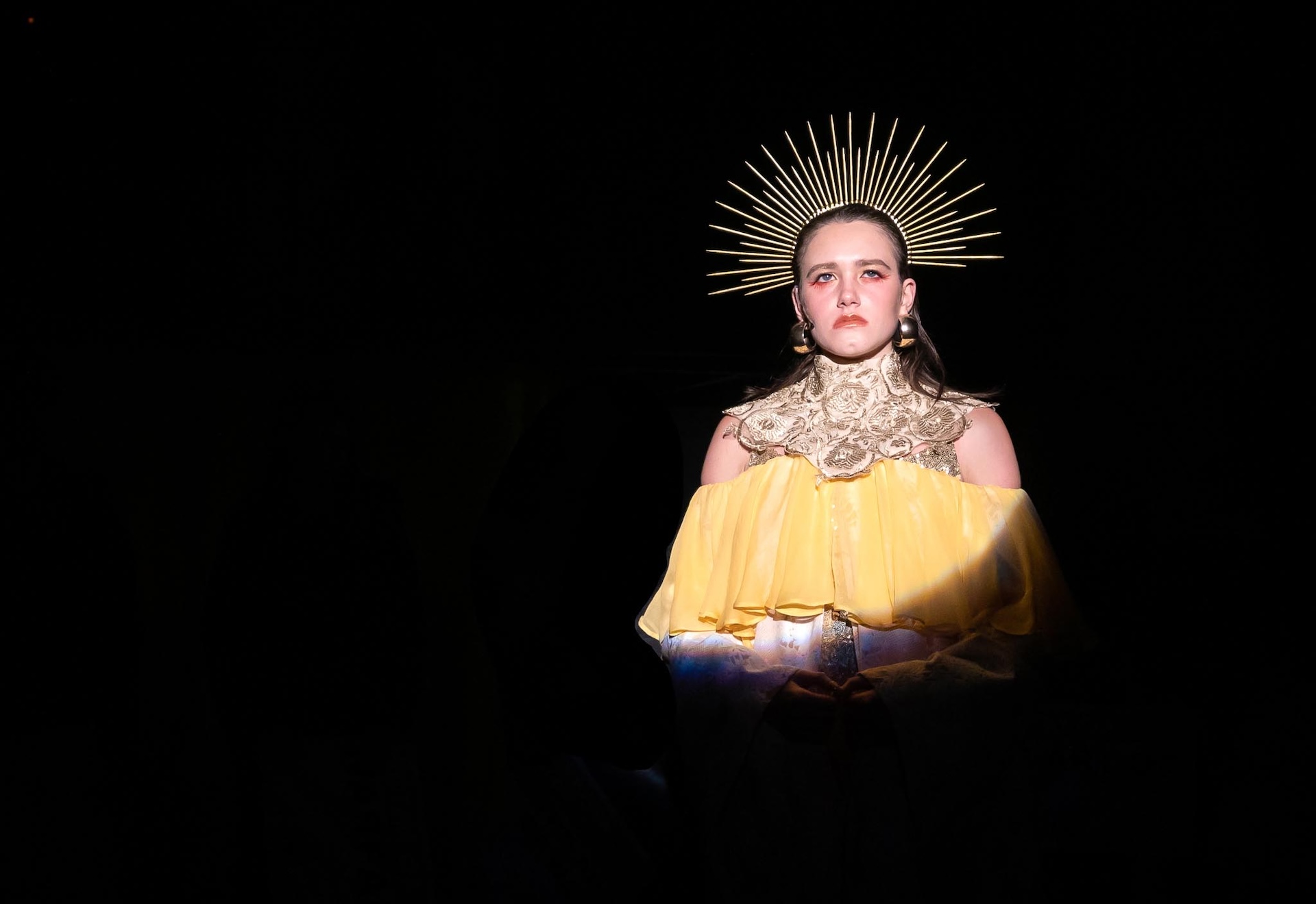 Actor wearing yellow dress and semi-circle crown