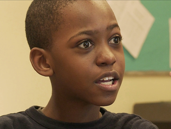 Film Still from Shakespeare at the Point. Image of boy talking with passion. 