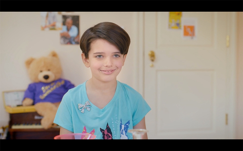 Close up of a young boy smiling in front of a teddy bear.