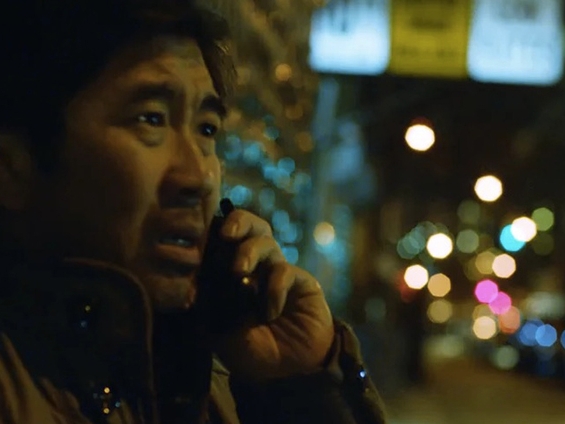 Film still from New Year. Image of man on cell phone on the street. 