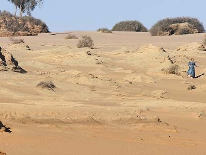 Film film from Full Circle. Image of woman running down hill in an arid climate. 