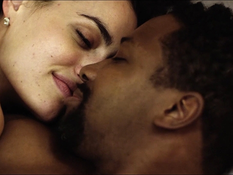 Film still from Modern Love. Close up image of couple (man and woman) kissing in bed. 