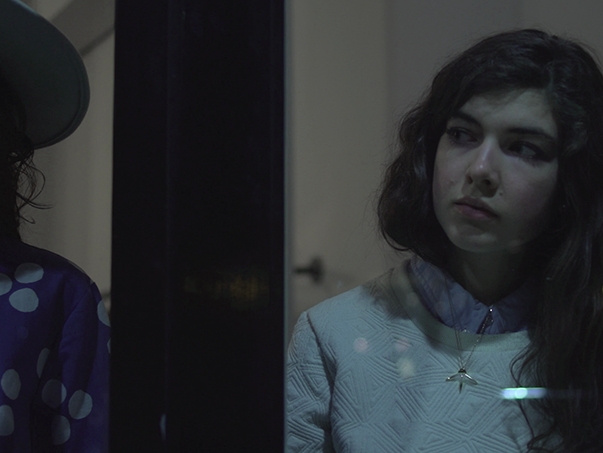 Film still from The Window Dresser. Image of woman's face reflected in a window.