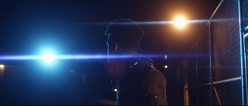 A young man looking off into the distance at a bright light.