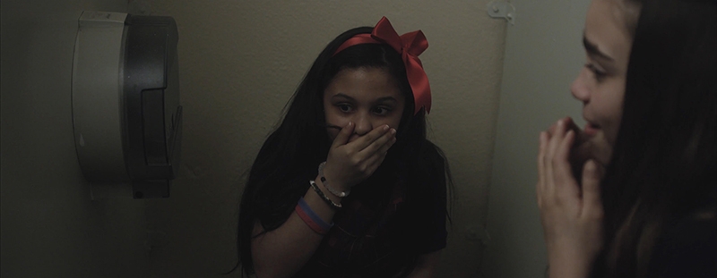 Two young girls in in a bathroom stall.