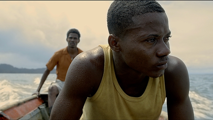 Film still of Manos Sucias, two men sitting on a boat.