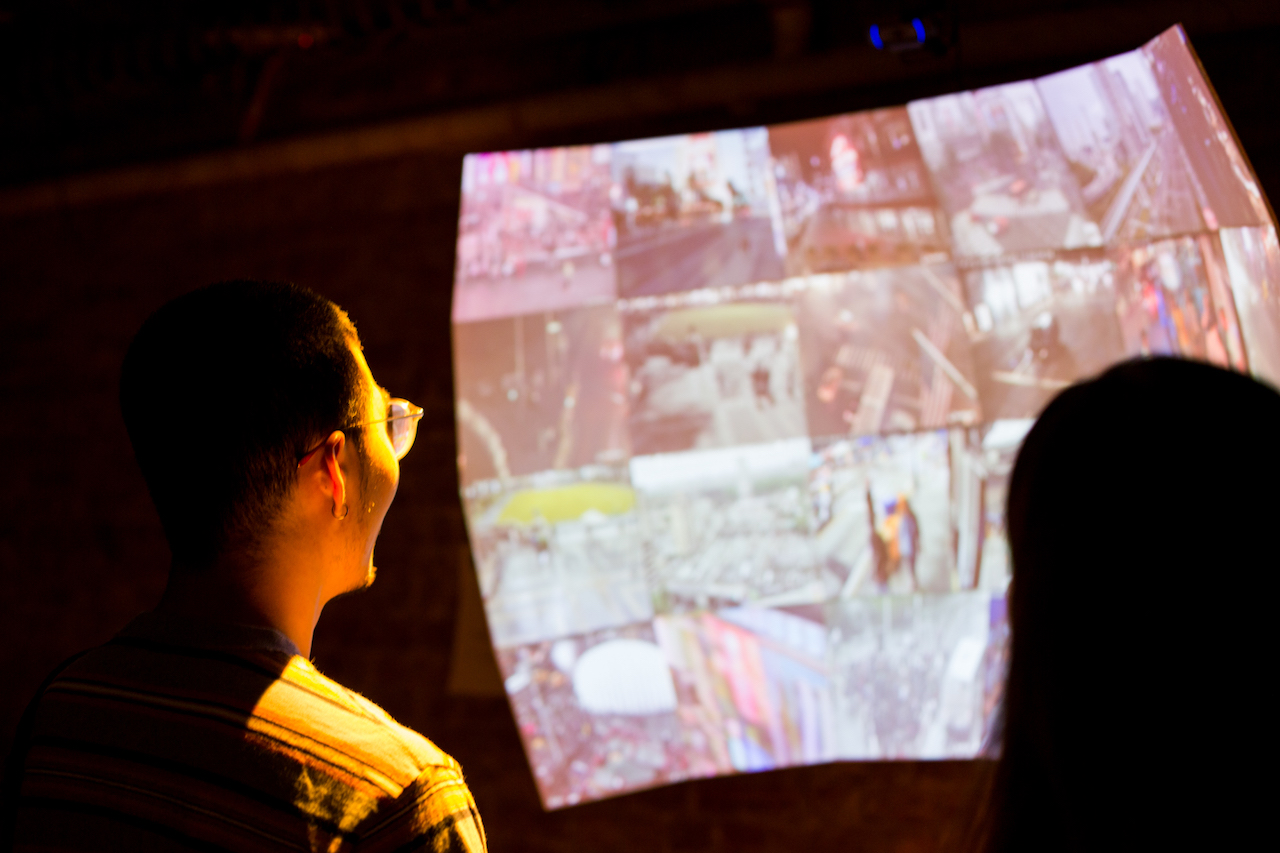 Man looks into projection with faces of different people