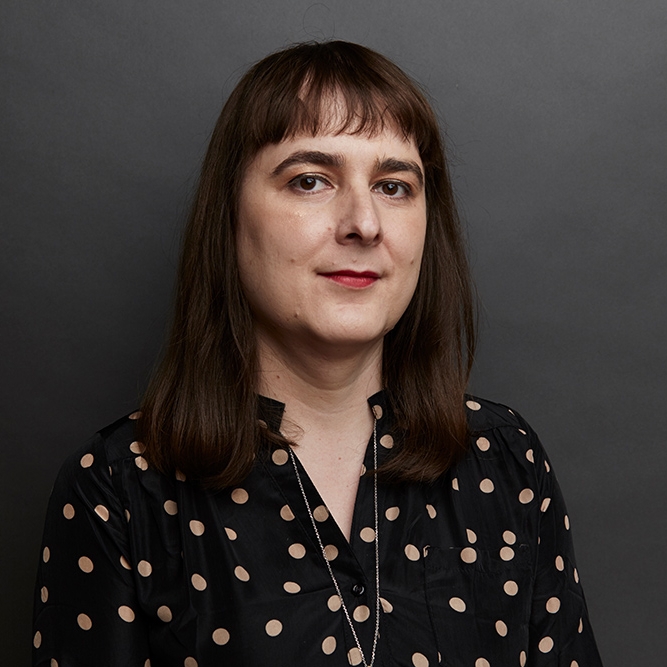 A woman grinning with a polka dot shirt