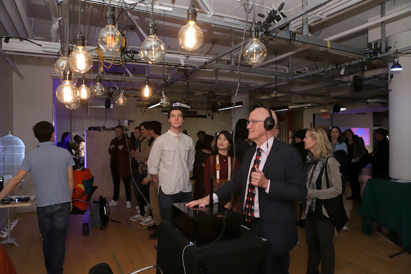 Andrew Hamilton wears headphones and looks at lit light bulbs