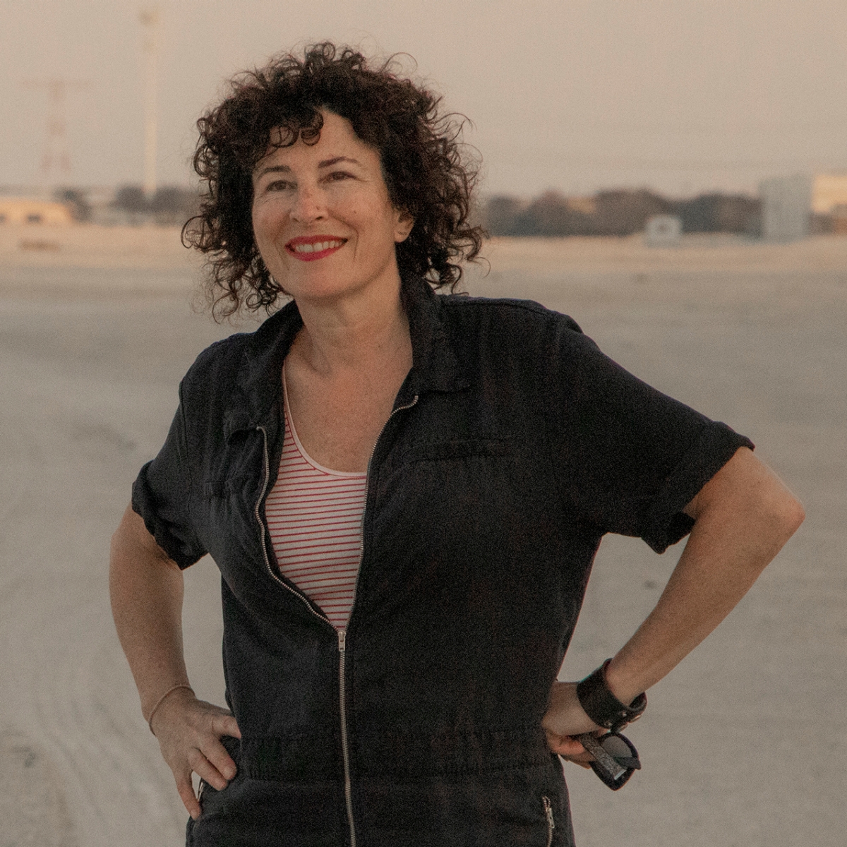 A woman wearing a black top, chunky necklace with arms crossed