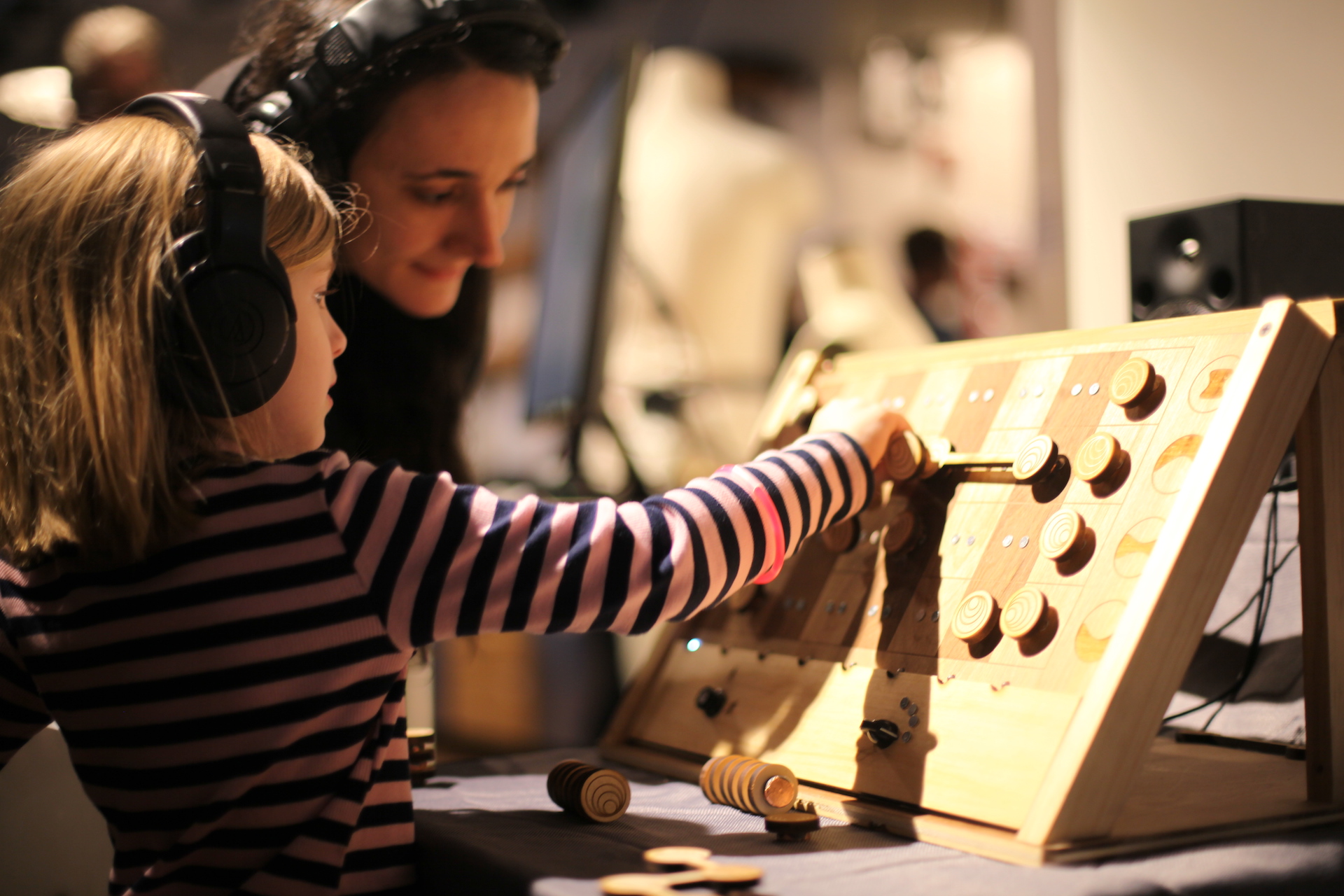 a young girl placing wooden magnetic pieces on a device while wearing headphones