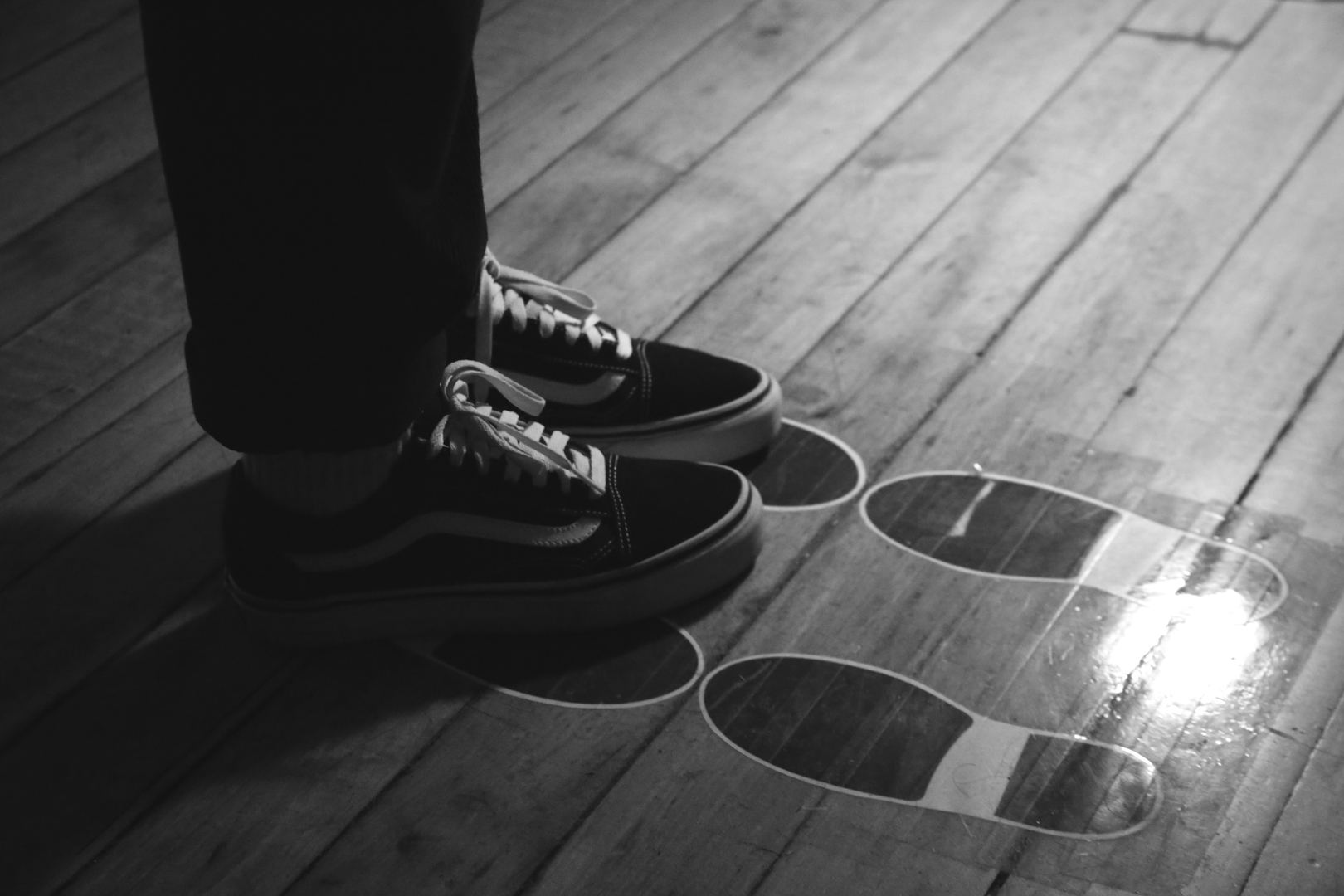 A person wearing shoes stepping on footprints on the floor