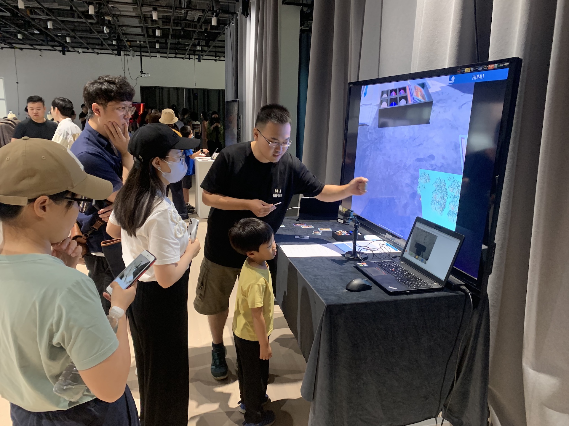 A man showing a child and other visitors a project on a TV