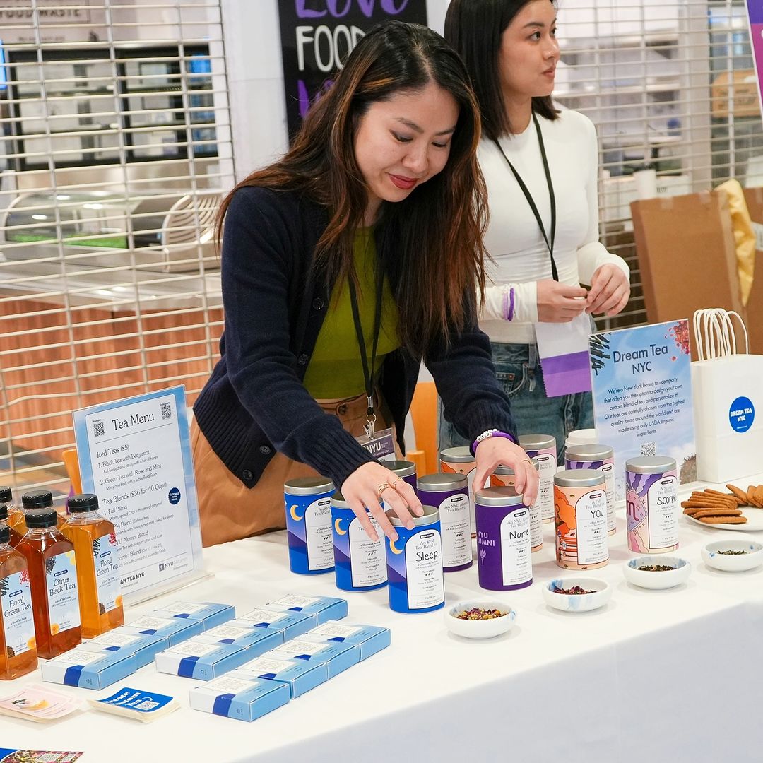 A woman behind a table presenting her tea cannisters from her business