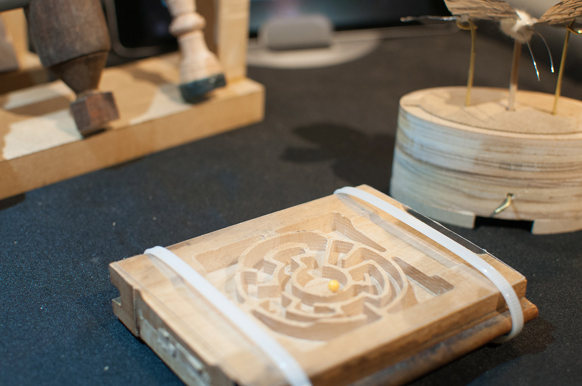 a wooden maze with a tiny yellow ball in the center