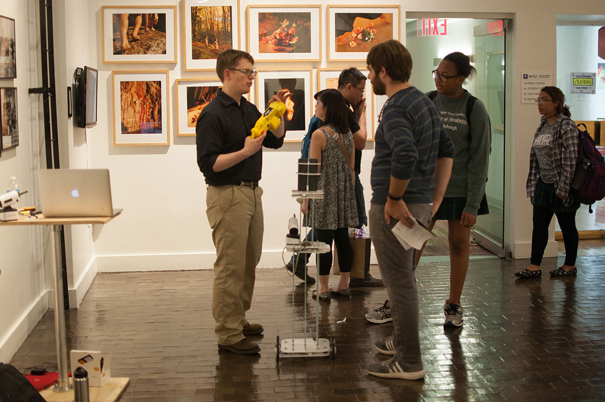 a man holding up a yellow device and talking to people