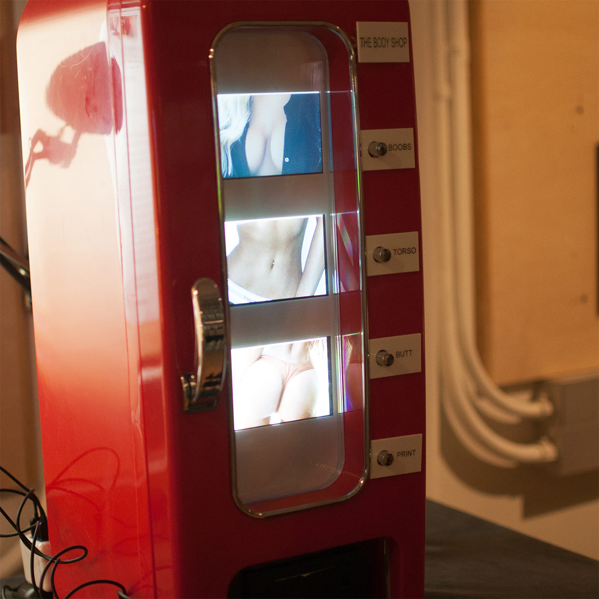 a vending machine showing 3 racy images of women's bodies