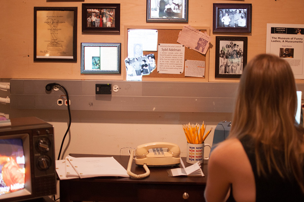 A woman sitting at a desk with a phone, pencils and picture frames