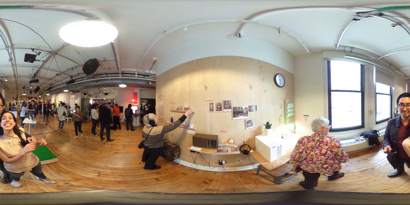 a 360 image of the hallway and people standing by projects at the show